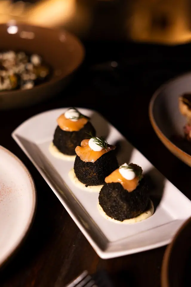 Trois arancini noirs au saumon fumé.