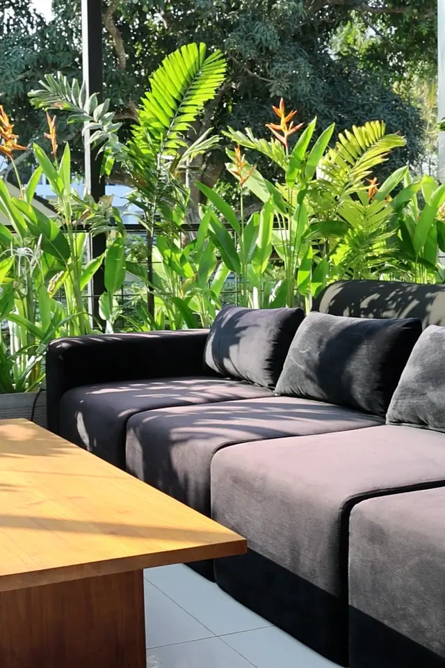 Un canapé à l’étage, au soleil, devant des plantes tropicales.