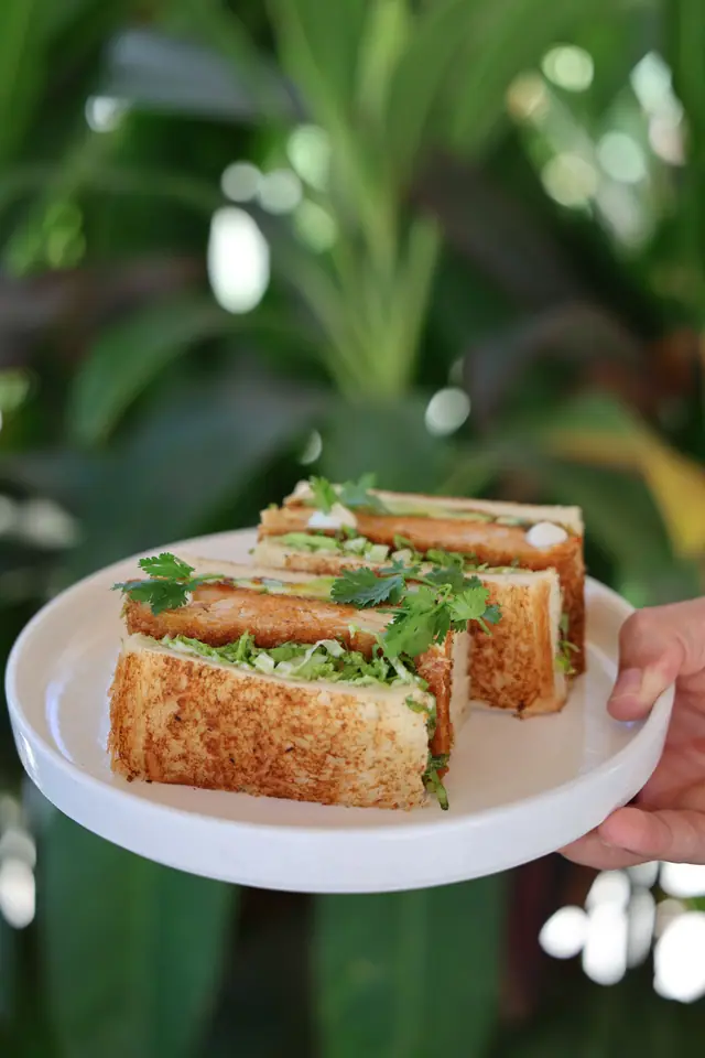 Un sando au poulet katsu coupé en trois, présenté dans le jardin.