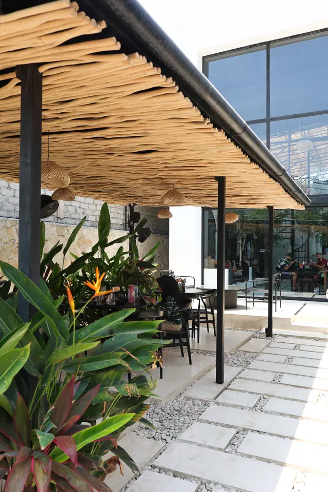 The terrace under the woven roof, with tropical plants.