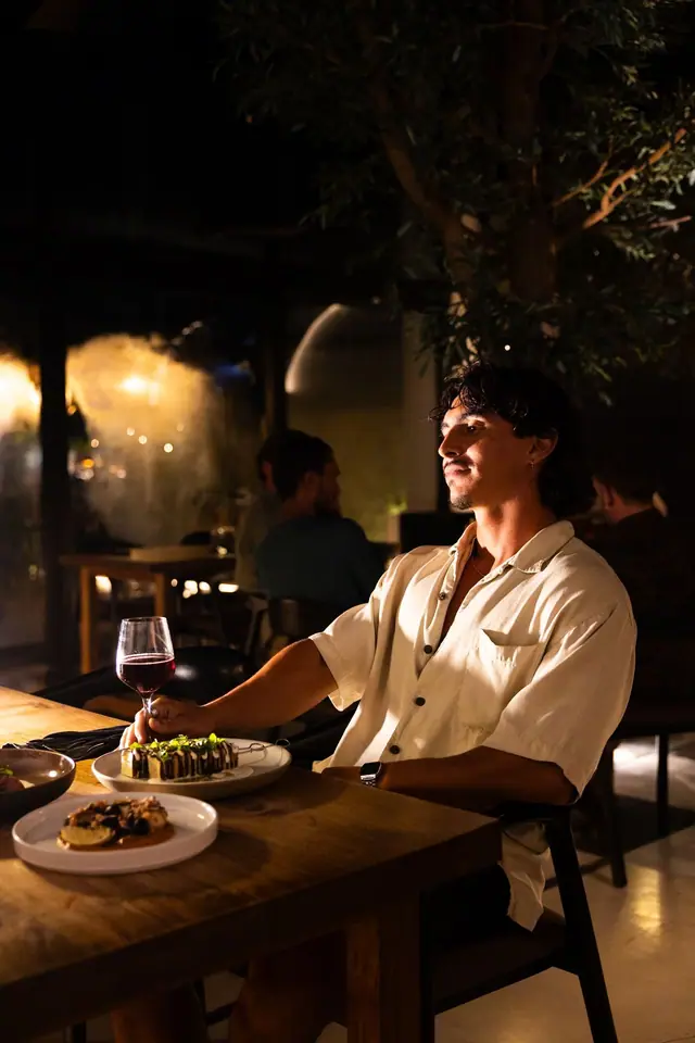 Un client à table sous l’arbre, dans la lumière chaude du soir.