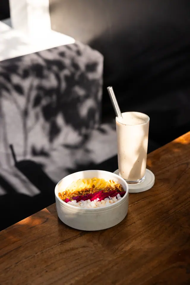 Un smoothie bowl et un shake dans la lumière filtrée par les feuilles.