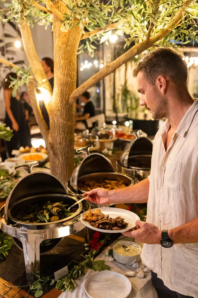 Un client se sert au buffet sous l’arbre illuminé.