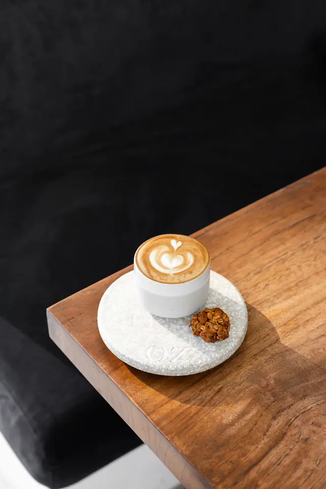 Un flat white sur le coin d’une table en bois.