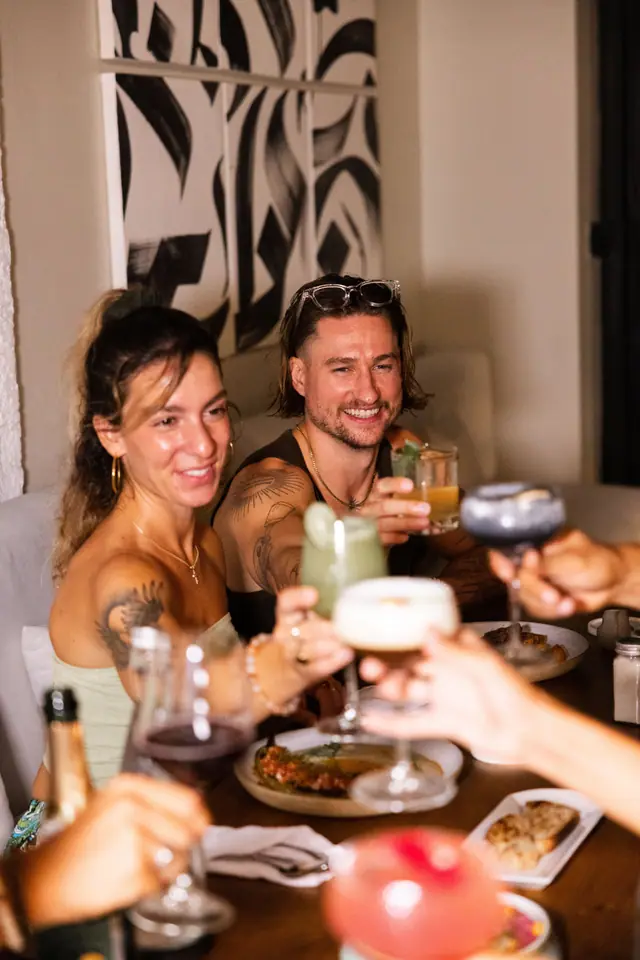 Des amis trinquent au-dessus d’une table pleine de plats.