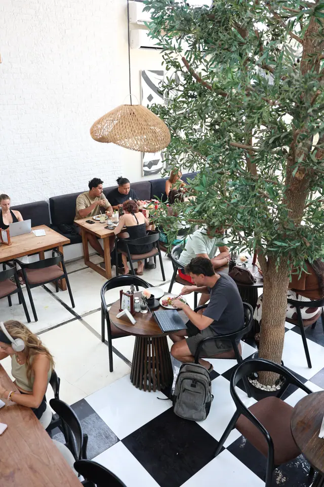 La salle vue d’en haut : des clients mangent et travaillent entre les arbres.