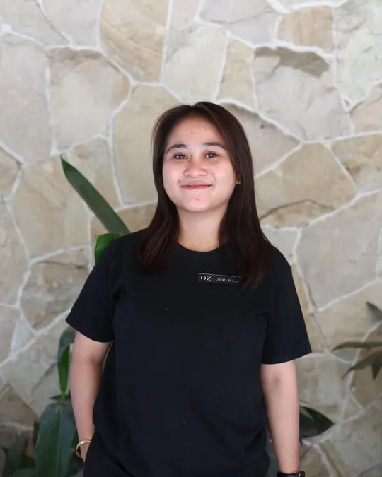 Diane in front of a stone wall, smiling, in the black OZ shirt.