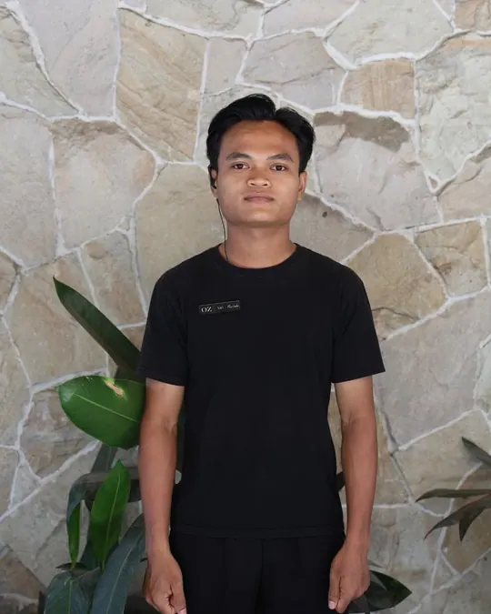 Yan in front of a stone wall, in the black OZ shirt.