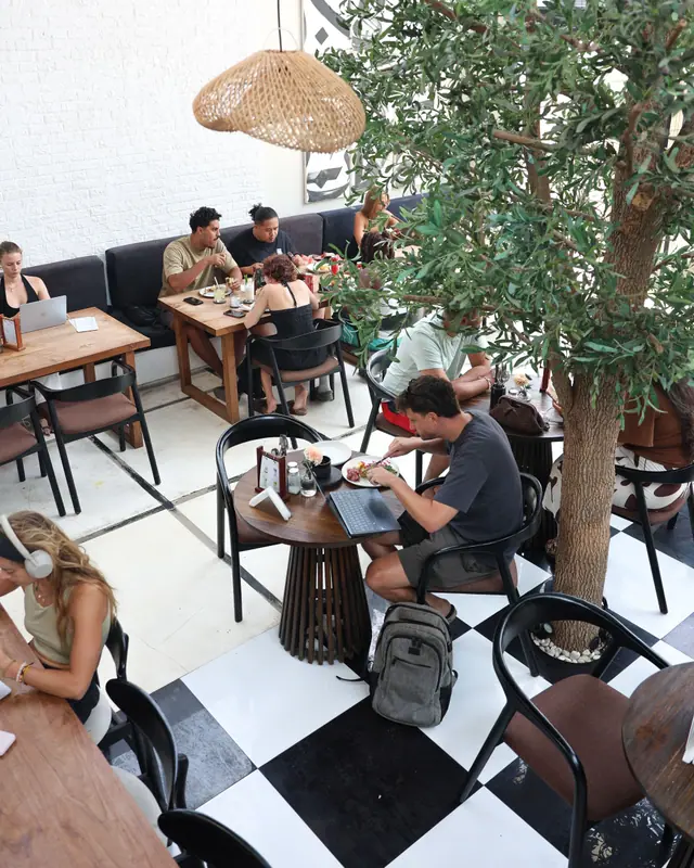 Ruangan dilihat dari atas: tamu makan dan bekerja di antara pepohonan.