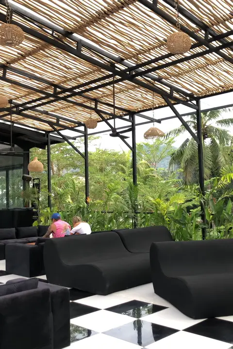 La caméra parcourt le lounge à l’étage, de la vue sur la verdure jusqu’aux canapés.